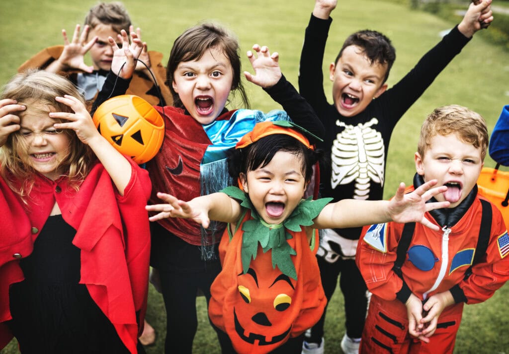Children in Halloween costumes celebrating outdoors during Trick or Treat event.